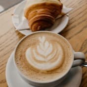 A latte beside a croissant on a café table