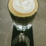 A flat white in a glass on a counter