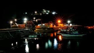 A boat by a dock at night, used as a series still