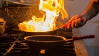 Flames rising from a pan in a kitchen, used as a show still